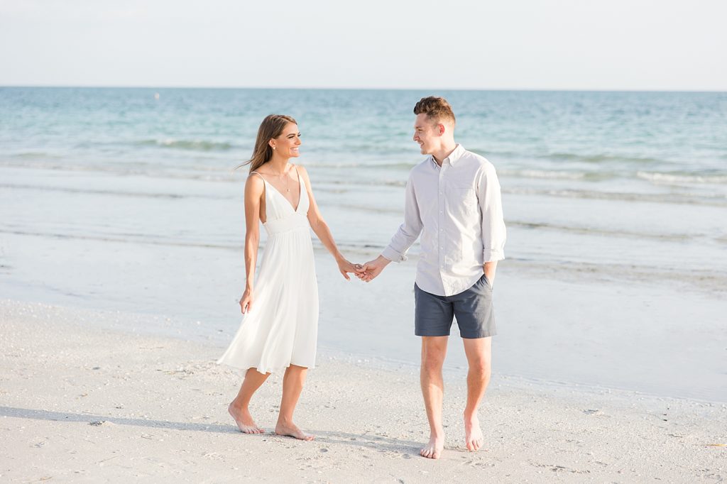A couple walking down Lido Key Beach during the engagement pictures. 