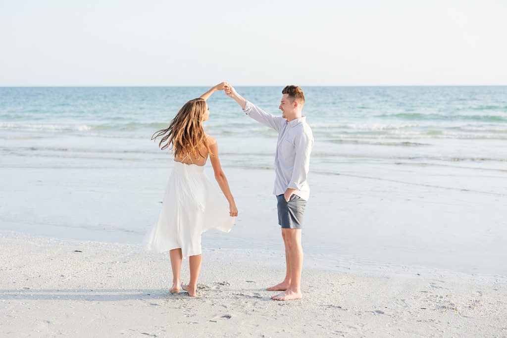 a couple spinning and dancing on Lido Key Beach during their engagement session. 