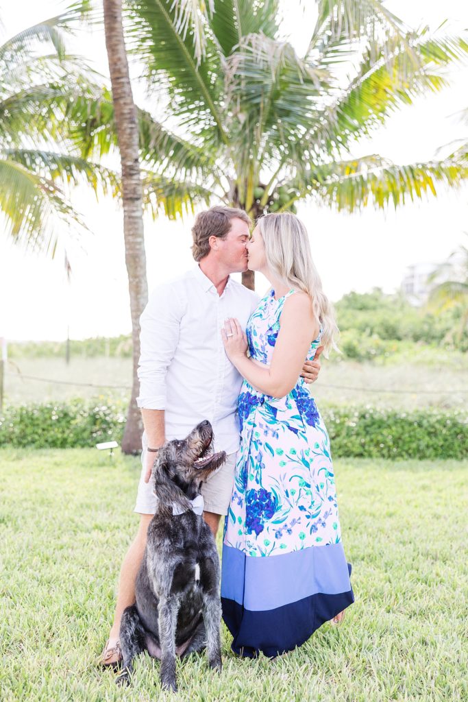 A couple kissing with their dog watching during their Fort Myers Beach Engagement Session. 