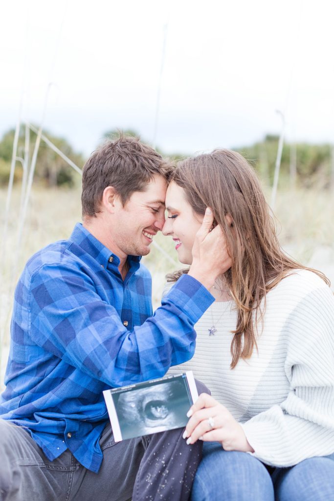 A couple hugging while holding their ultrasound of their baby. 