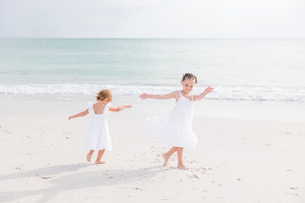Little girls spinning in circles on Bean Point Beach on Anna Maria Island in Sarasota, Florida. 