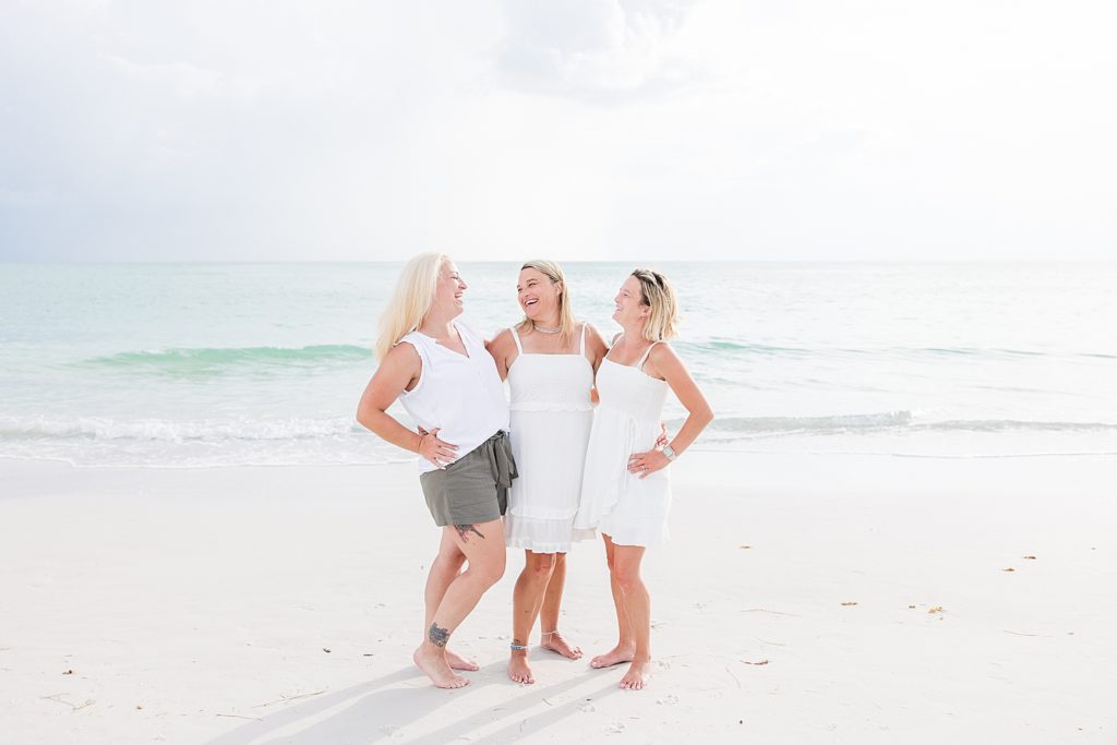 Mother and daughters hugging and laughing on the beach. 