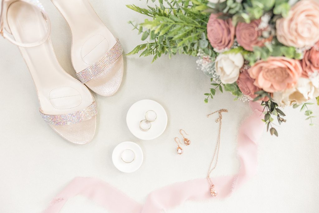 A picture of all the brides details such as her shoes, flowers, and rings. 