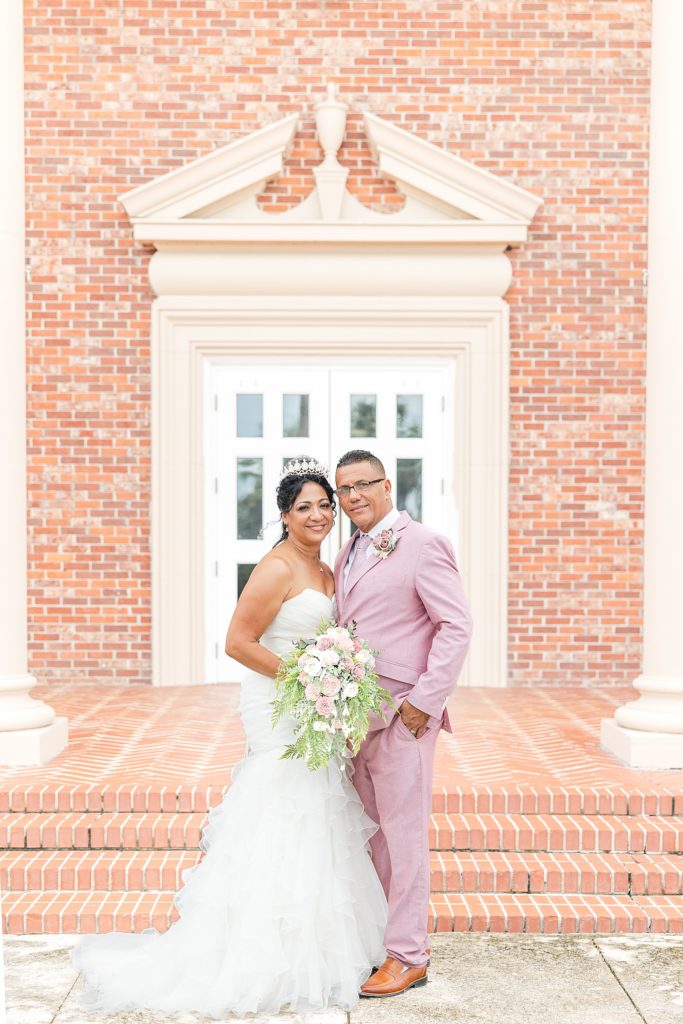 A bride and groom smiling in front of the brick church in west bradenton, Florida. 