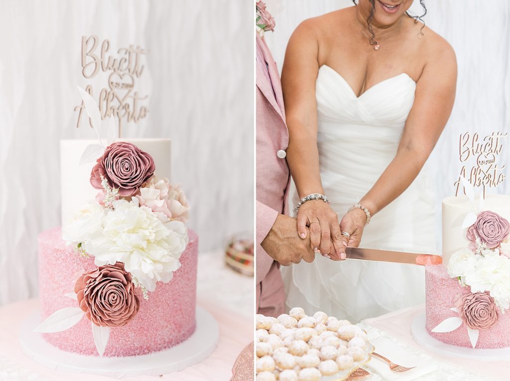 A pink wedding cake with white and pink wooden flowers on the front. 