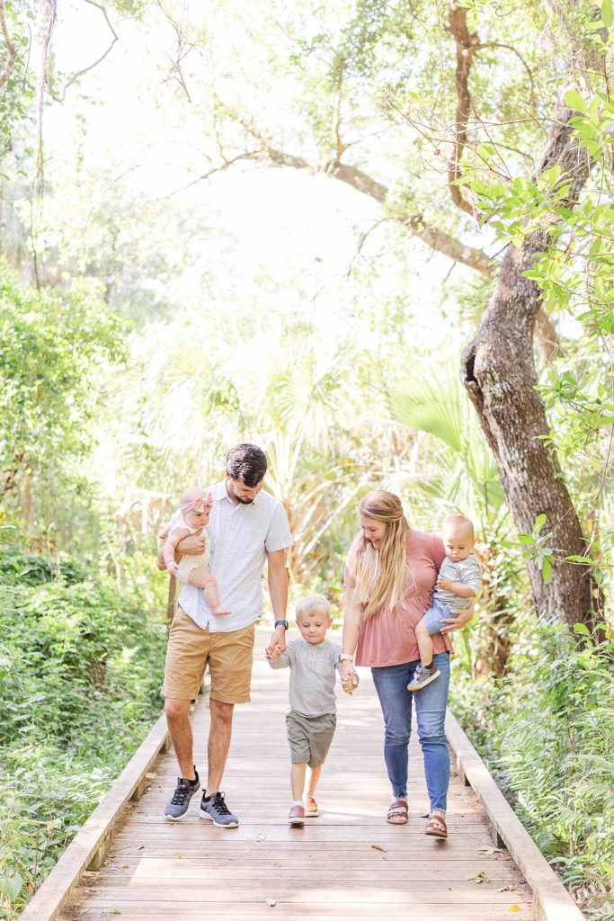 A family holding hands and walking down a path during their Family Pictures in North Fort Myers