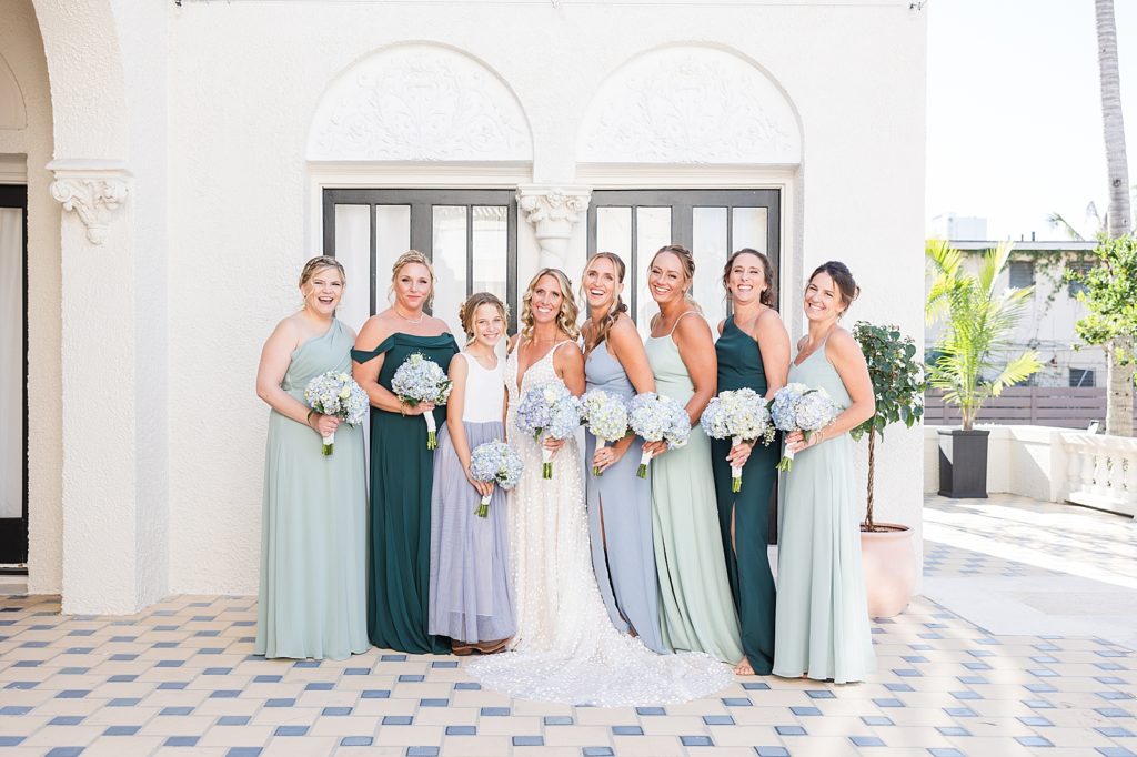The bride and bridesmaids smiling in different shades of blue and green. 