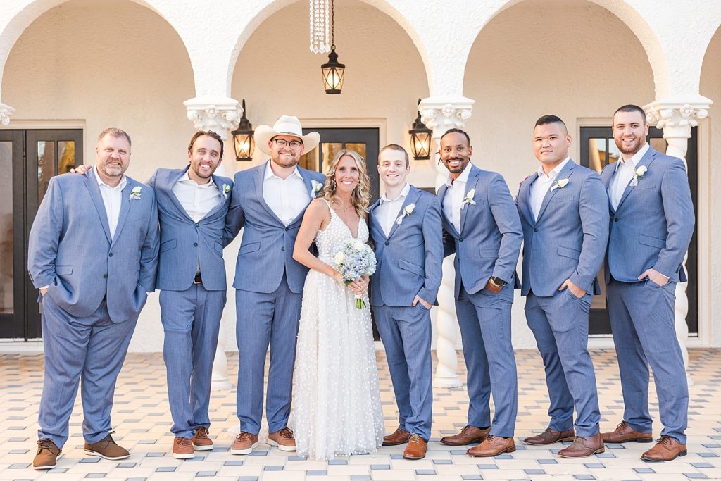 The bride smiling with the groomsmen. 