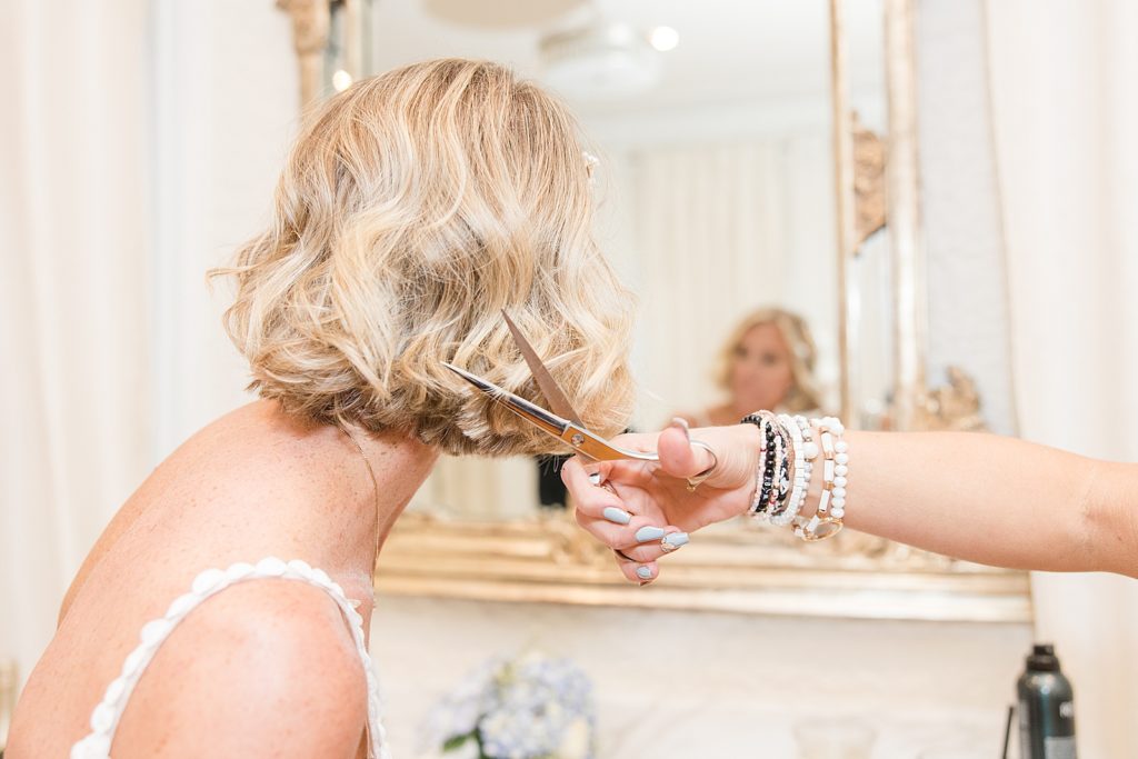 The bride cutting her hair at her wedding. 