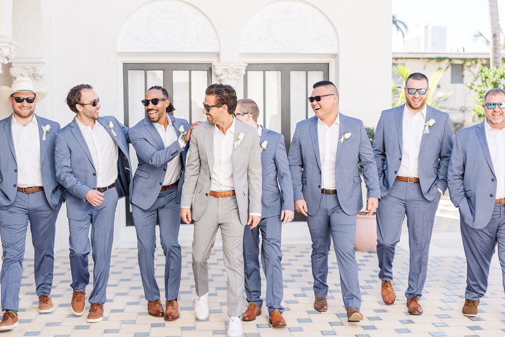 The groom and groomsmen walking with sunglasses on. 