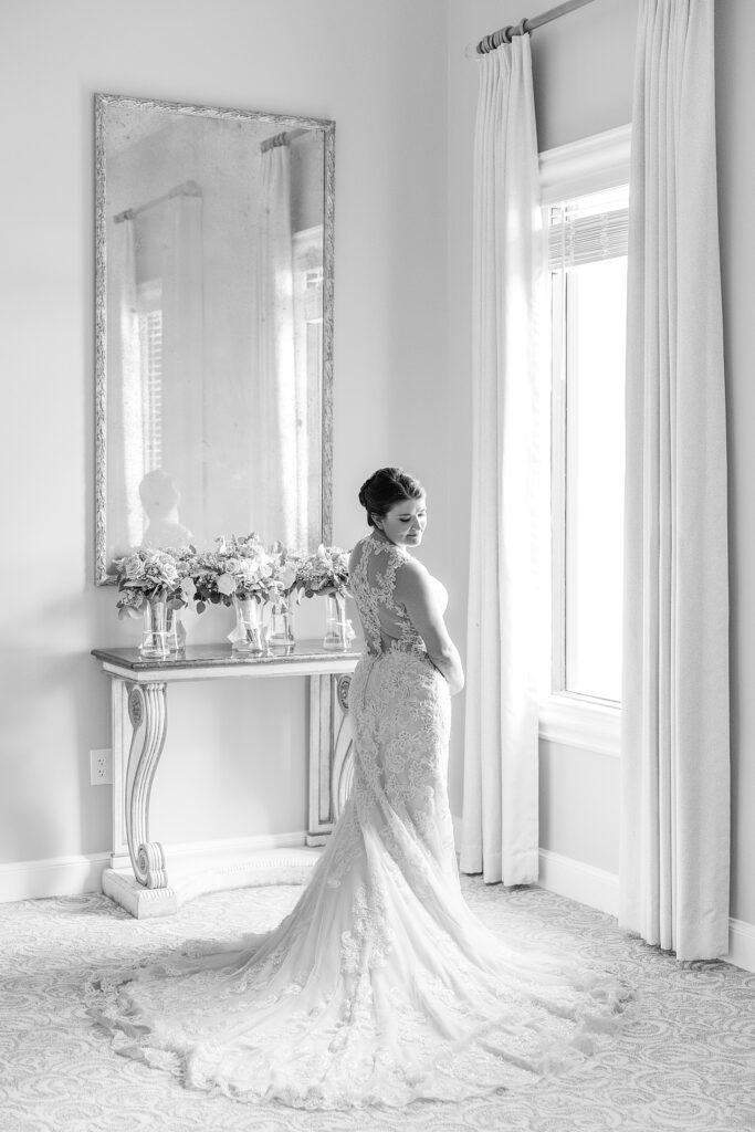 bride standing in her wedding dress by a window. 