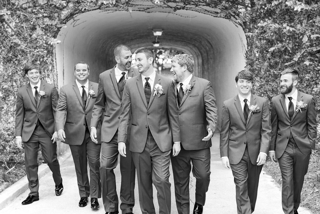 groom and groomsmen walking in front of a tunnel.  