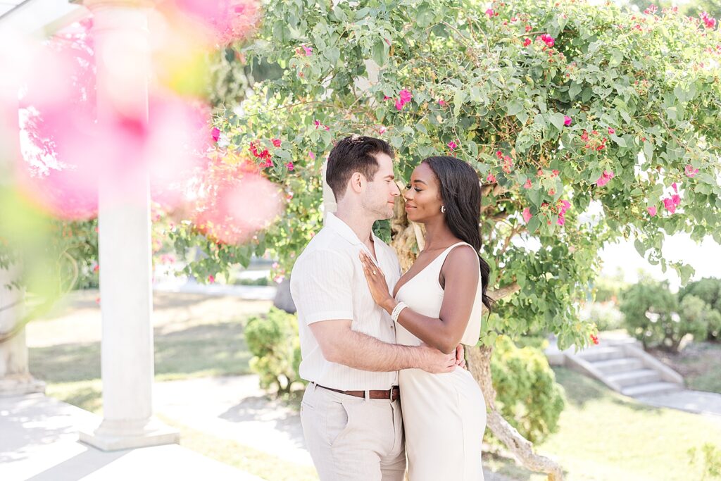 Couple smiling at each other surrounded by pink flowers.