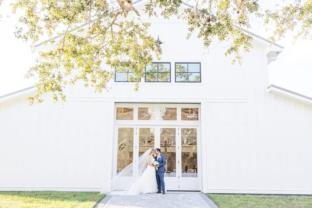A bride and groom standing in front of Kings Crossing Barn.