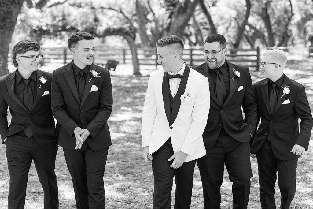 black and white picture of the groomsmen walking and laughing. 