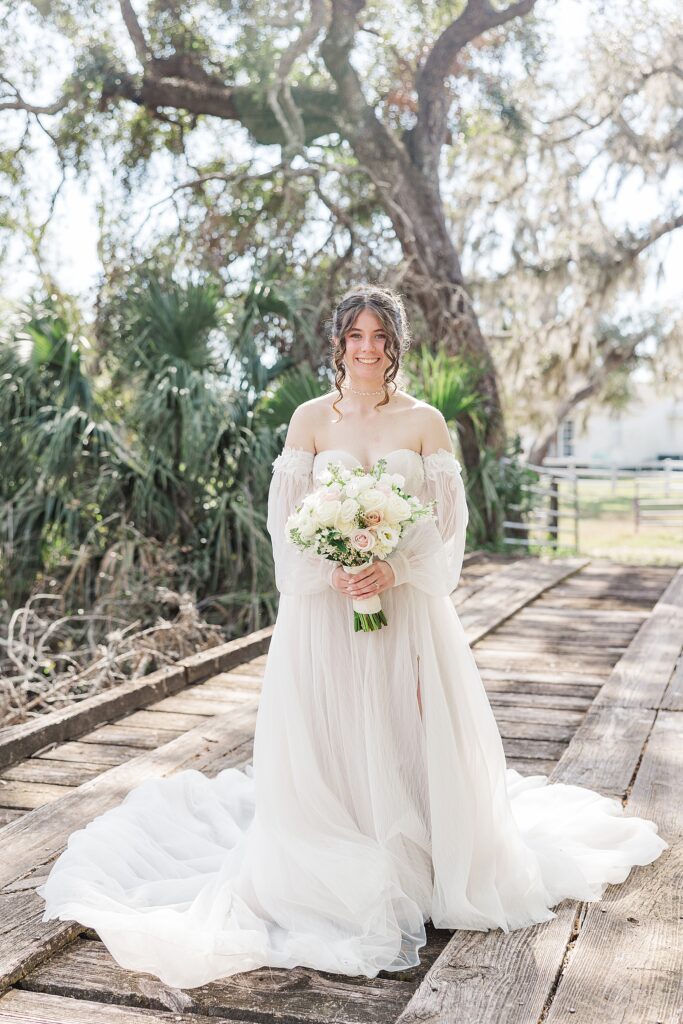 Bride smiling while standing on a bridge. 