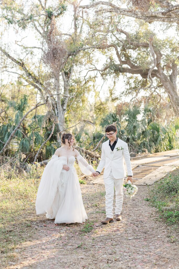 Bride and groom walking by a bridge. 