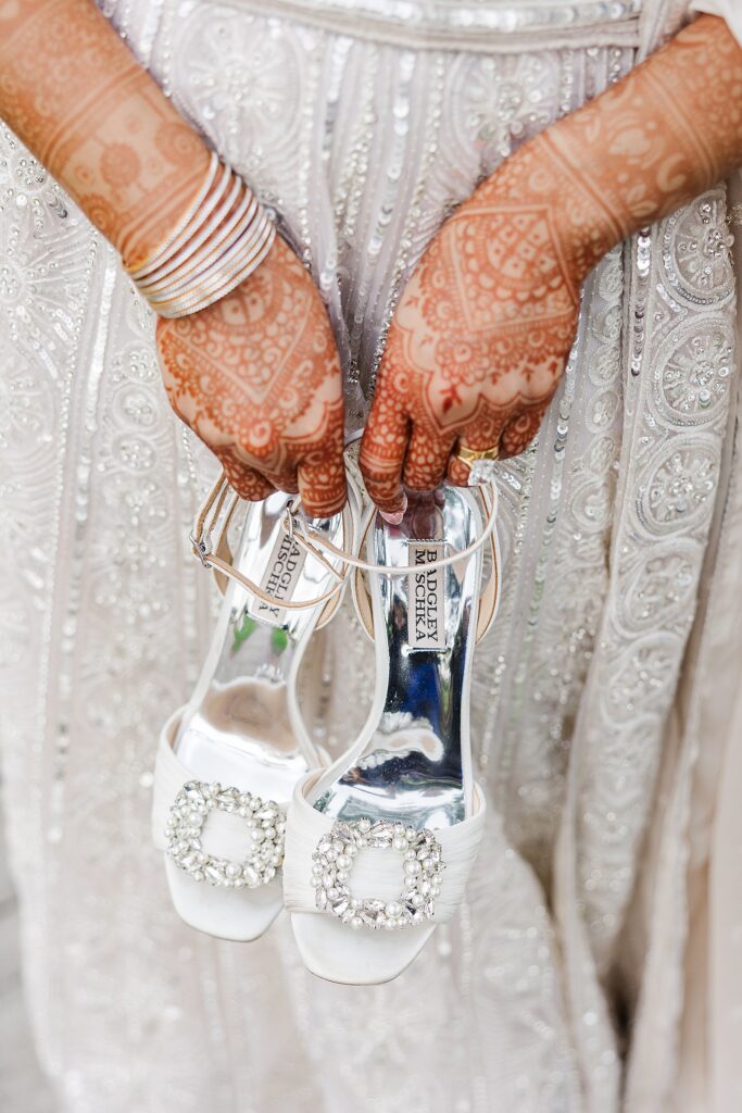 Indian bride holding her Badgley Mischka wedding heels in her hands done with Henna.