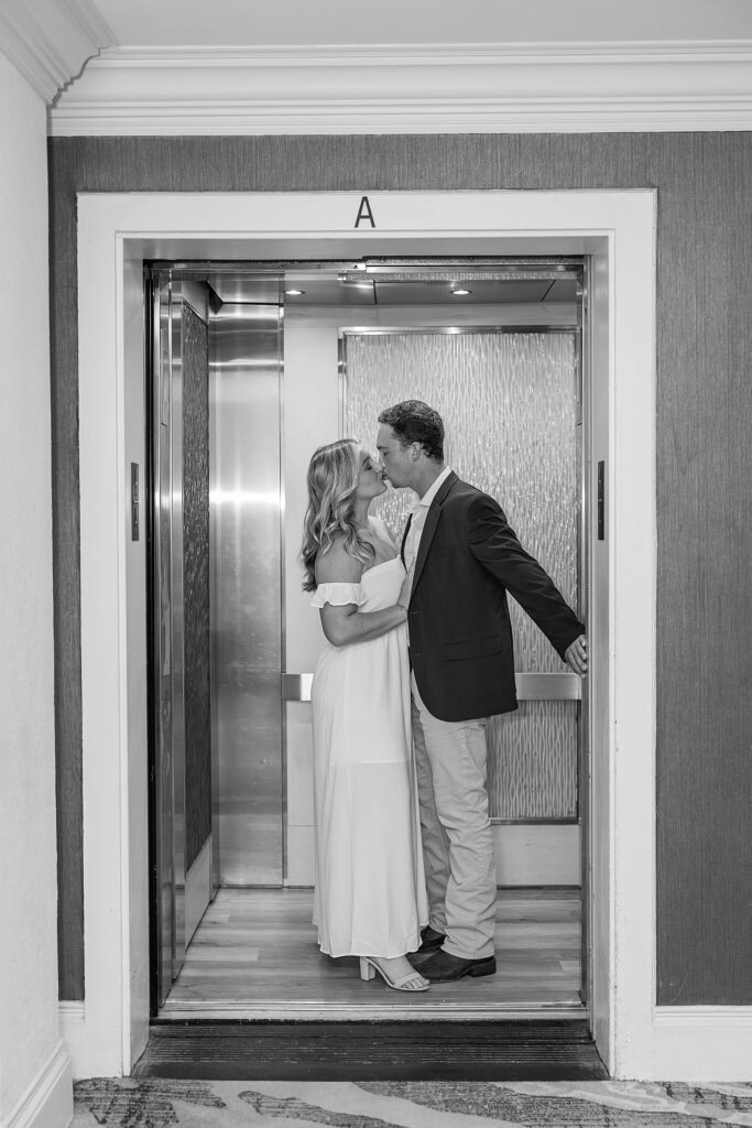 black and white picture of couple kissing in a elevator.